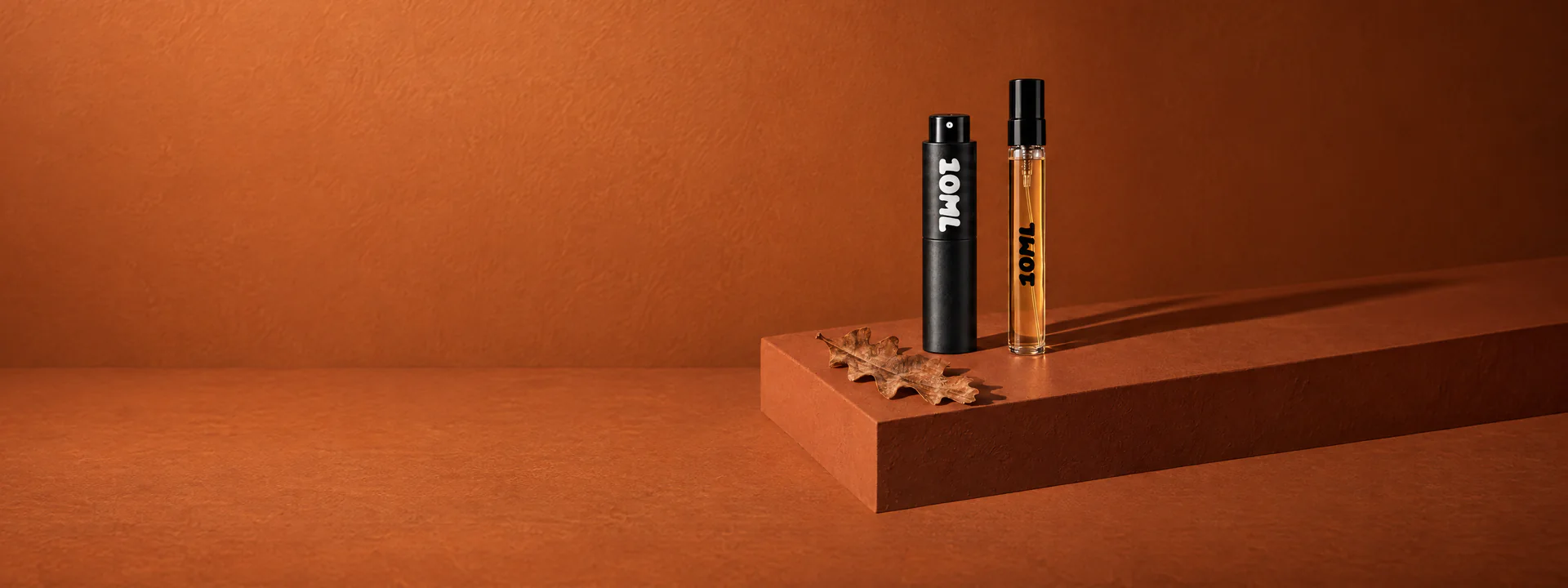 A 10ML atomiser and an amber sample vial with an oak leaf on a rust-coloured plinth