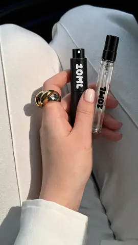 A hand holding a black 10ML atomiser and a clear 10ML sample vial
